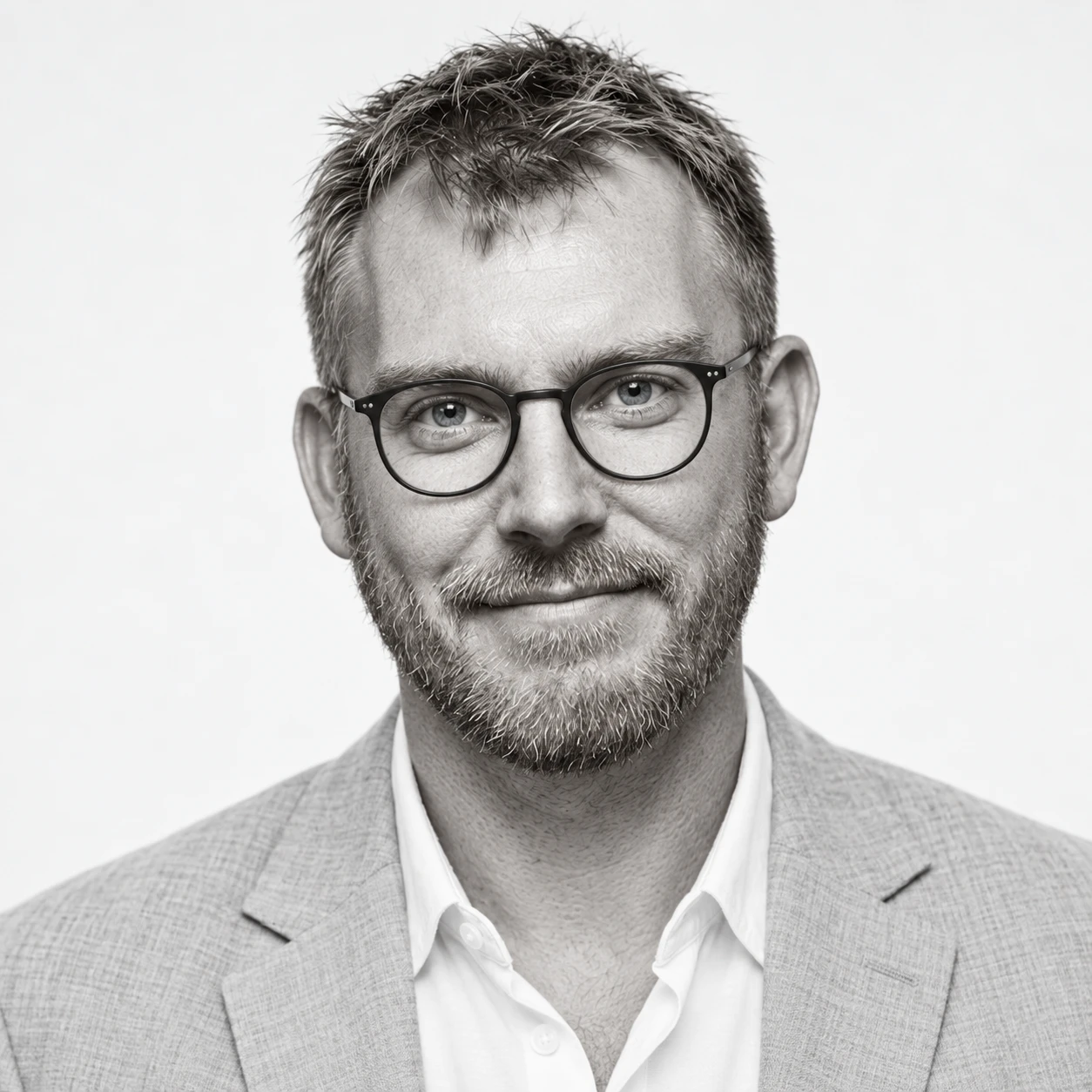 Micah Iverson, black and white portrait in glasses and a linen blazer